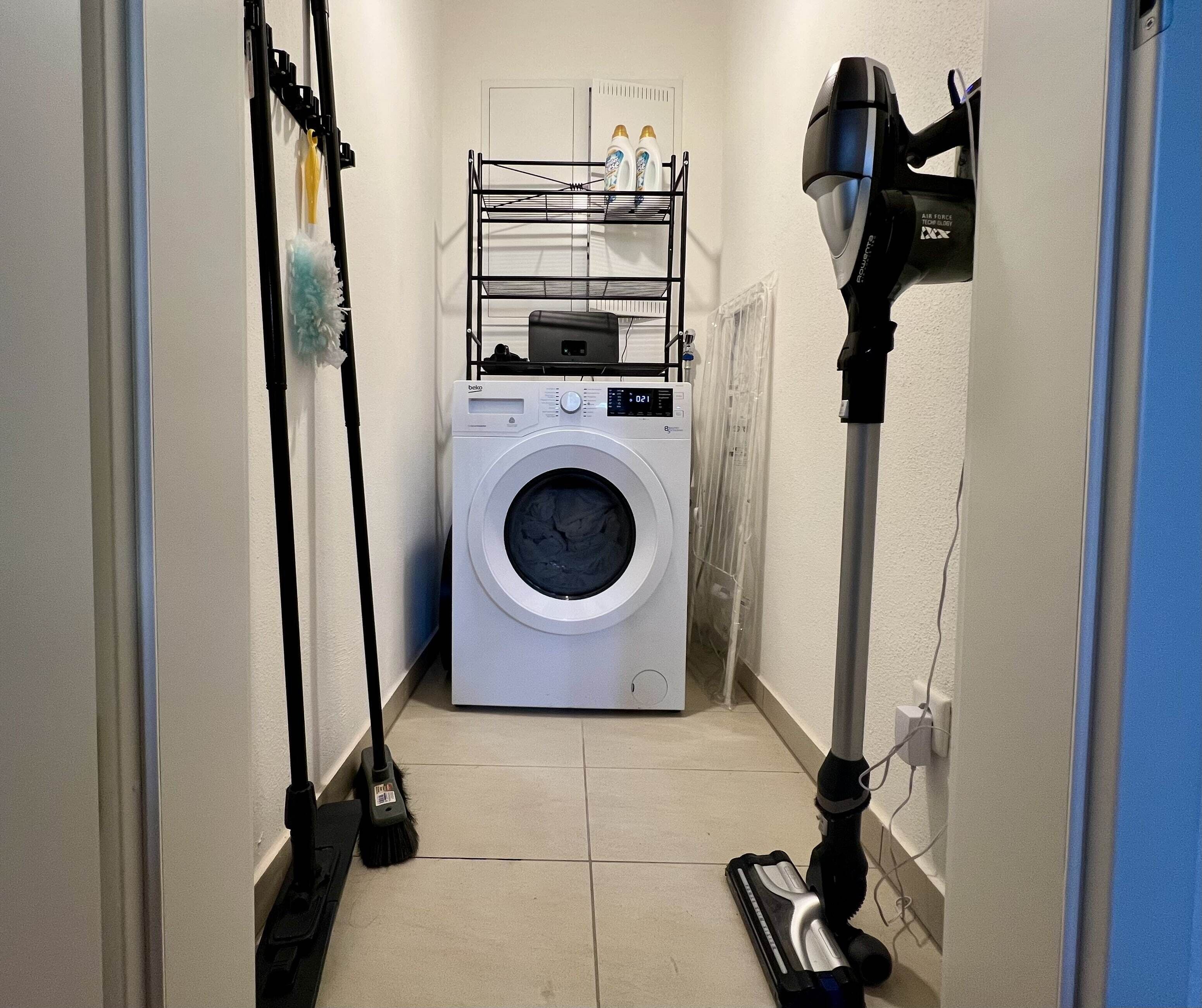 Una sala amb rentadora de càrrega frontal, un escorredor i un aspirador.