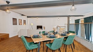 A dining area with a wooden table set for four, green upholstered chairs, and pendant lighting. - flair Alte Brauerei I Old town I free parking lot I coffee I WiFi I Xbox IDisney (Kitzingen)