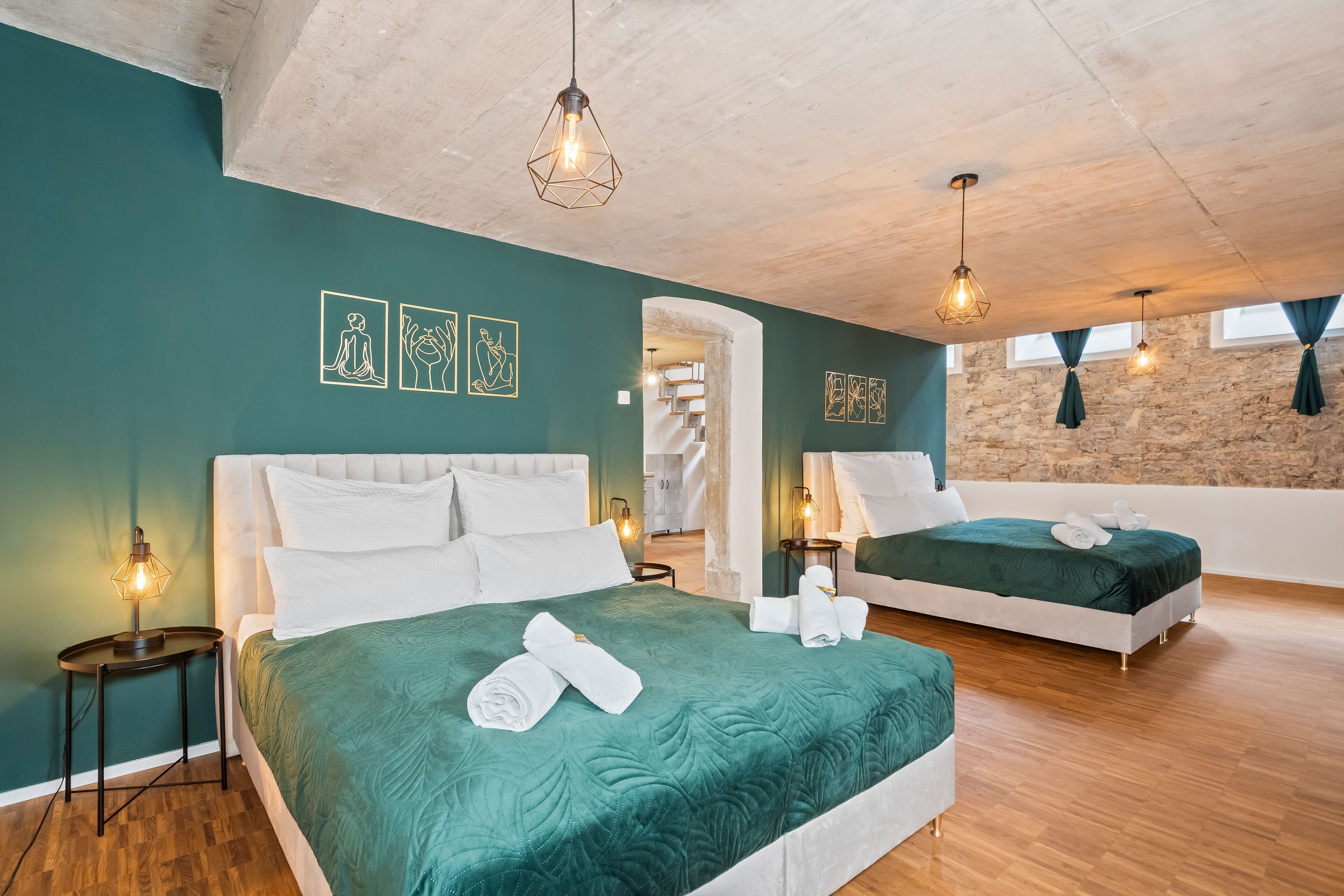 Camera d'albergo con due letti, una scala e un muro in pietra.