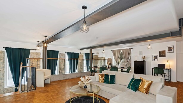 A spacious living room with a white sofa, a glass coffee table, and a black rug. There is a staircase with a metal railing leading to an upper level. - flair Alte Brauerei I Old town I free parking lot I coffee I WiFi I Xbox IDisney (Kitzingen)