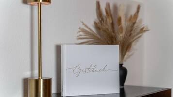 A white framed book with the word "Gästebuch" on it, placed on a dark surface next to a gold-colored floor lamp.