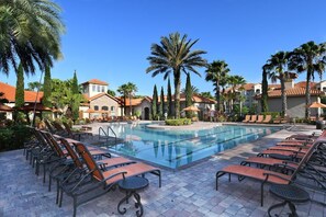 Relax by the resort pool surrounded by palm trees and lounge chairs.