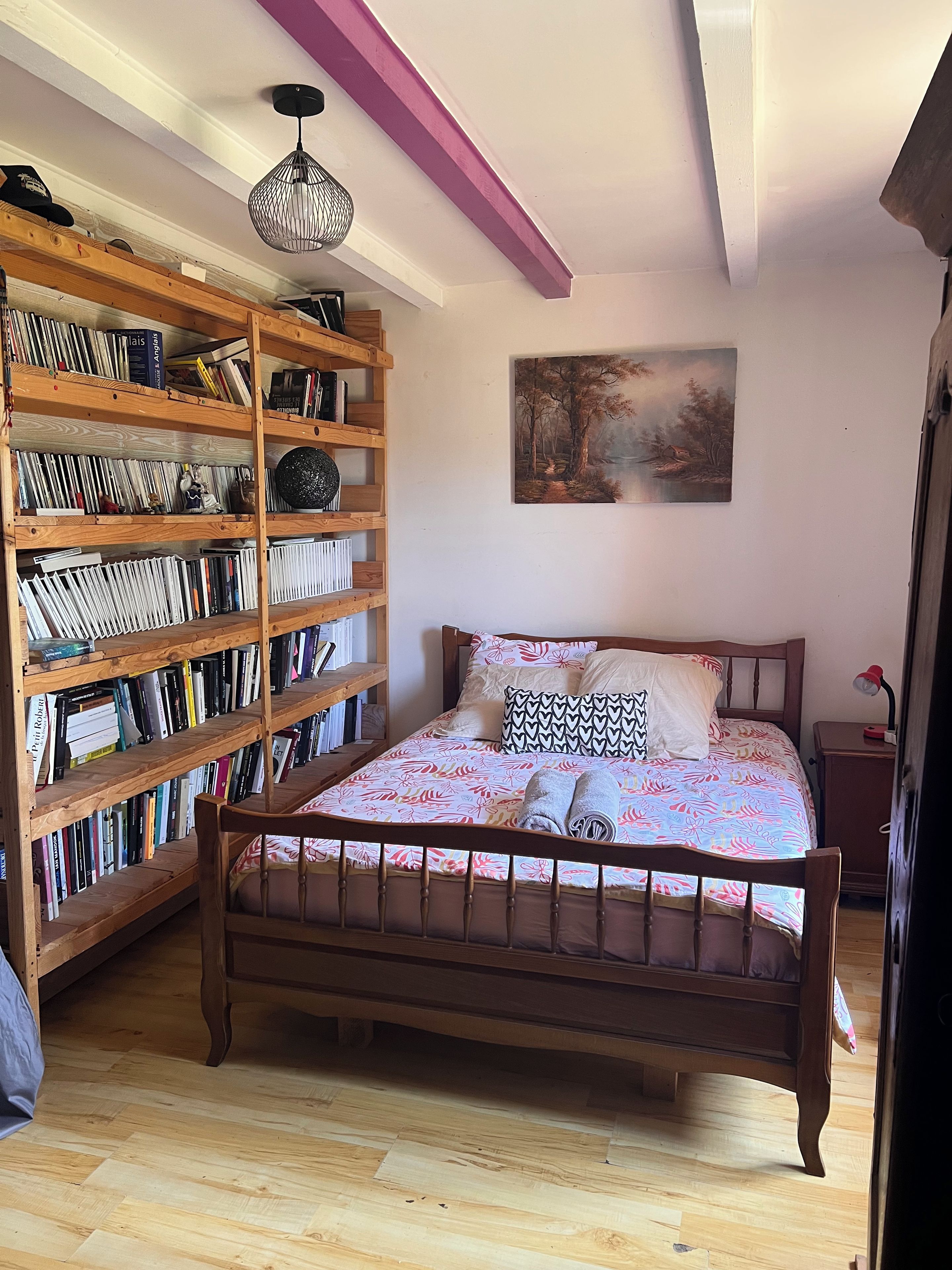 Ein Schlafzimmer mit einem hölzernen Bett, einem Bücherregal und einem Bild an der Wand.