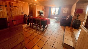 A wooden interior with a dining table, chairs, a television, and a barrel. - Aux Songes D'élise, Une, Maison Familiale au Coeur du Plateau des Mille Étangs (Belmont)