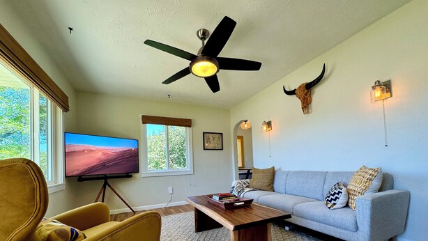 Una sala de estar con televisor, sofá, mesa de centro y ventilador de techo.