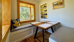 Una habitación acogedora con un banco de madera, una mesita y una ventana con vistas a árboles.