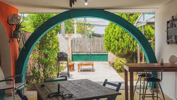 An outdoor patio area with a wooden table, chairs, and a grill. - Casa Samay Cozumel (Cozumel)