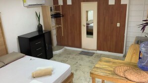 A bedroom with a bed, a wooden dresser, a desk with a water bottle, and a door with a mirror. - Casa Samay Cozumel (Cozumel)