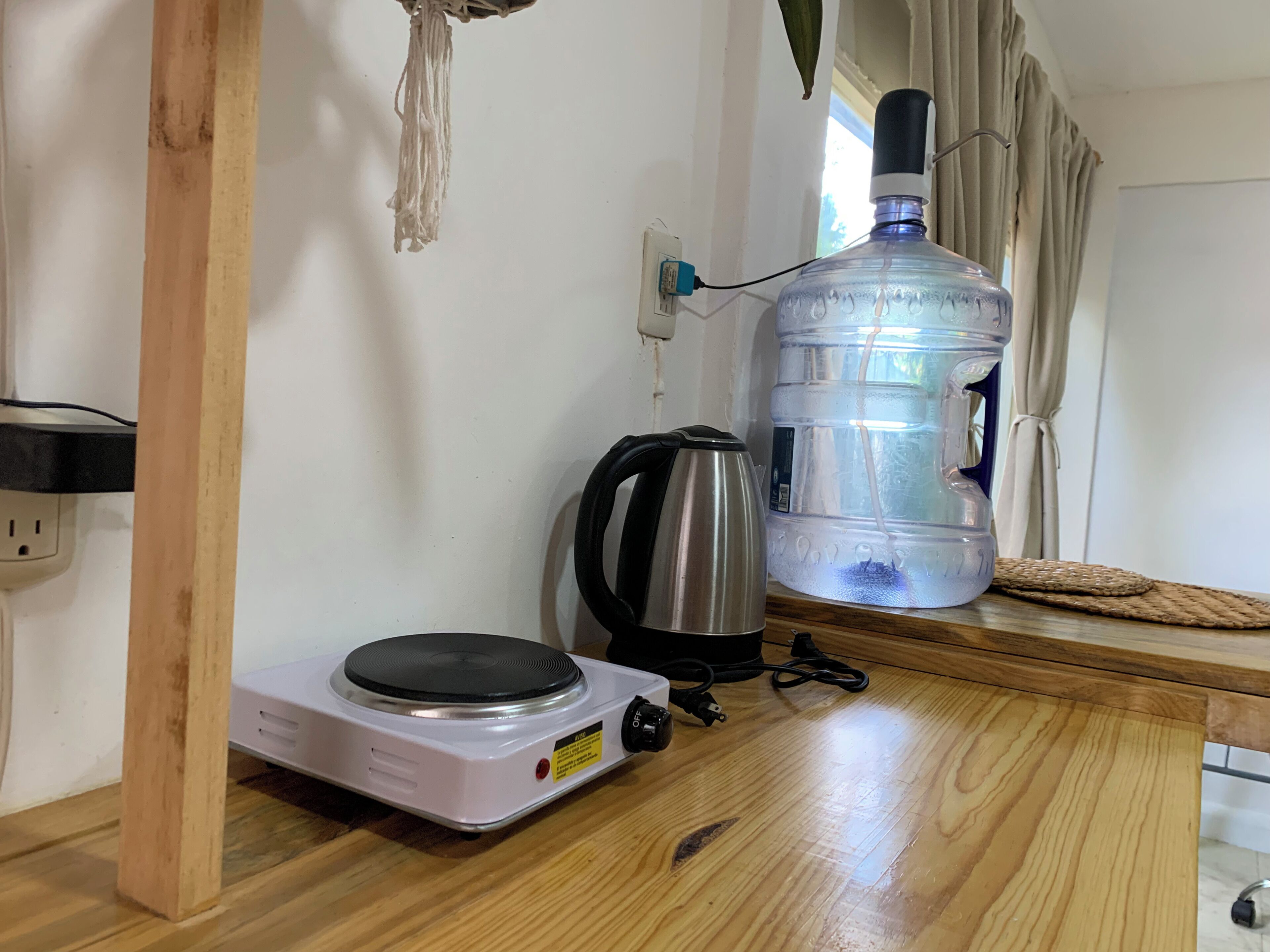 A kitchenette with a portable electric stove, a kettle, and a large water dispenser.