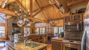 A spacious kitchen with granite countertops, stainless steel appliances, and wooden beams. - Red Stag Lodge at Eagles Nest (Banner Elk)
