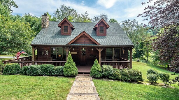 A log cabin with a stone chimney, a porch, and a gravel pathway leading to the entrance. - Country Life (Vilas)