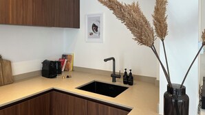 Une cuisine moderne dotée d’un évier encastré, de meubles en bois et d’un vase décoratif contenant des plantes séchées.