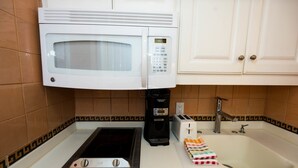A kitchen with a microwave, coffee maker, toaster, and sink.