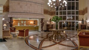 A lobby with a central round table, seating arrangements, and a large chandelier.
