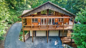 A two-story log cabin with a covered deck and a garage. - High On Cloud Nine (Boone)