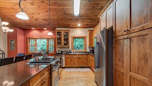 A kitchen with wooden cabinets, a stainless steel refrigerator, and a granite countertop. - High On Cloud Nine (Boone)