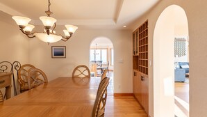 A dining area with a wooden table and chairs, a chandelier, and a view through an archway to another room. - Shooting Star Lodge (Boone)