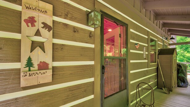 A wooden cabin with a welcoming sign featuring animal silhouettes and a star. - Kaylee's Kabin (Vilas)