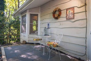 Une véranda avec une table et des chaises, une fenêtre, une guirlande et une pancarte de bienvenue.
