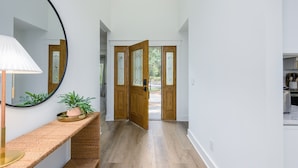 A hallway with a wooden door, a round mirror, a potted plant, and a lamp. - Close to the Beach! (Hilton Head Island)