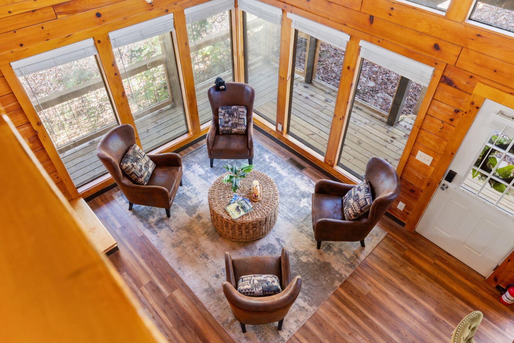 A cozy room with a wooden ceiling, large windows, and a central round table with chairs.