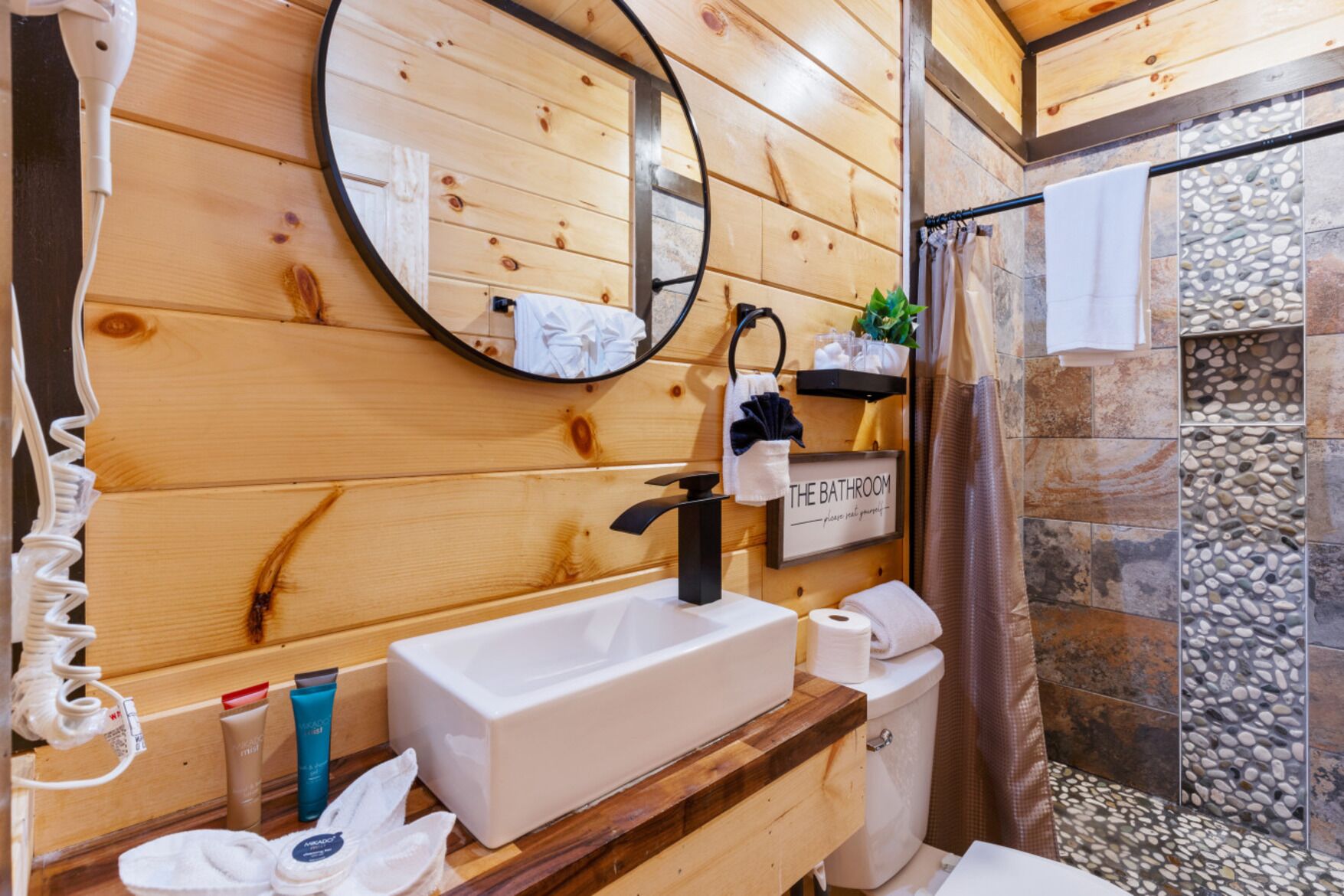 Ein Badezimmer aus Holz mit Waschbecken, Spiegel und Handtuchhalter.
