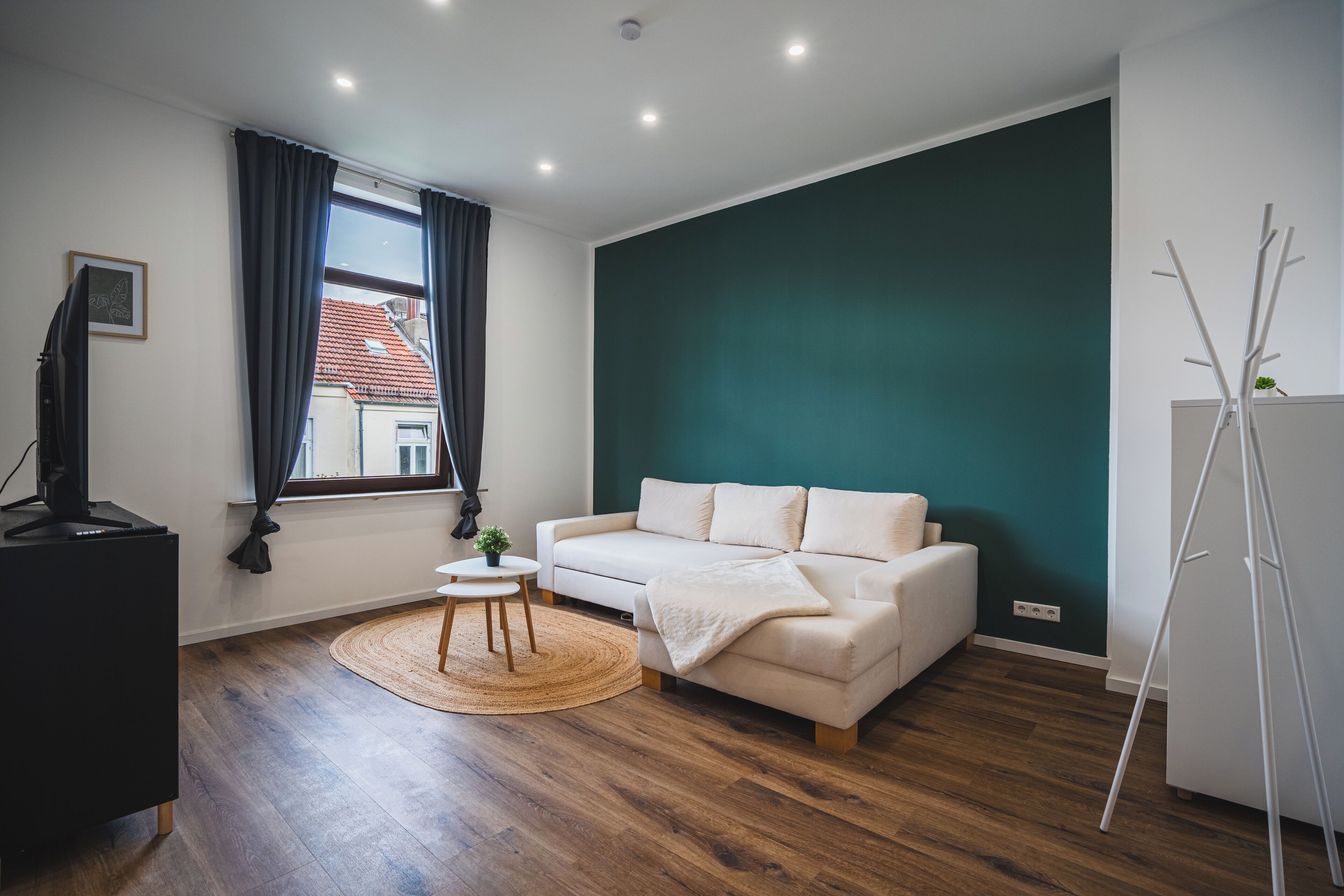 Een moderne woonkamer met een witte bank, een klein rond tafeltje en een staande lamp.