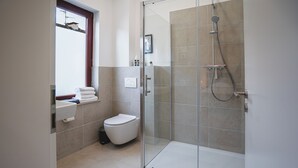 Une salle de bain moderne avec une douche à parois de verre, des toilettes et un lavabo équipé d’un porte-serviettes.