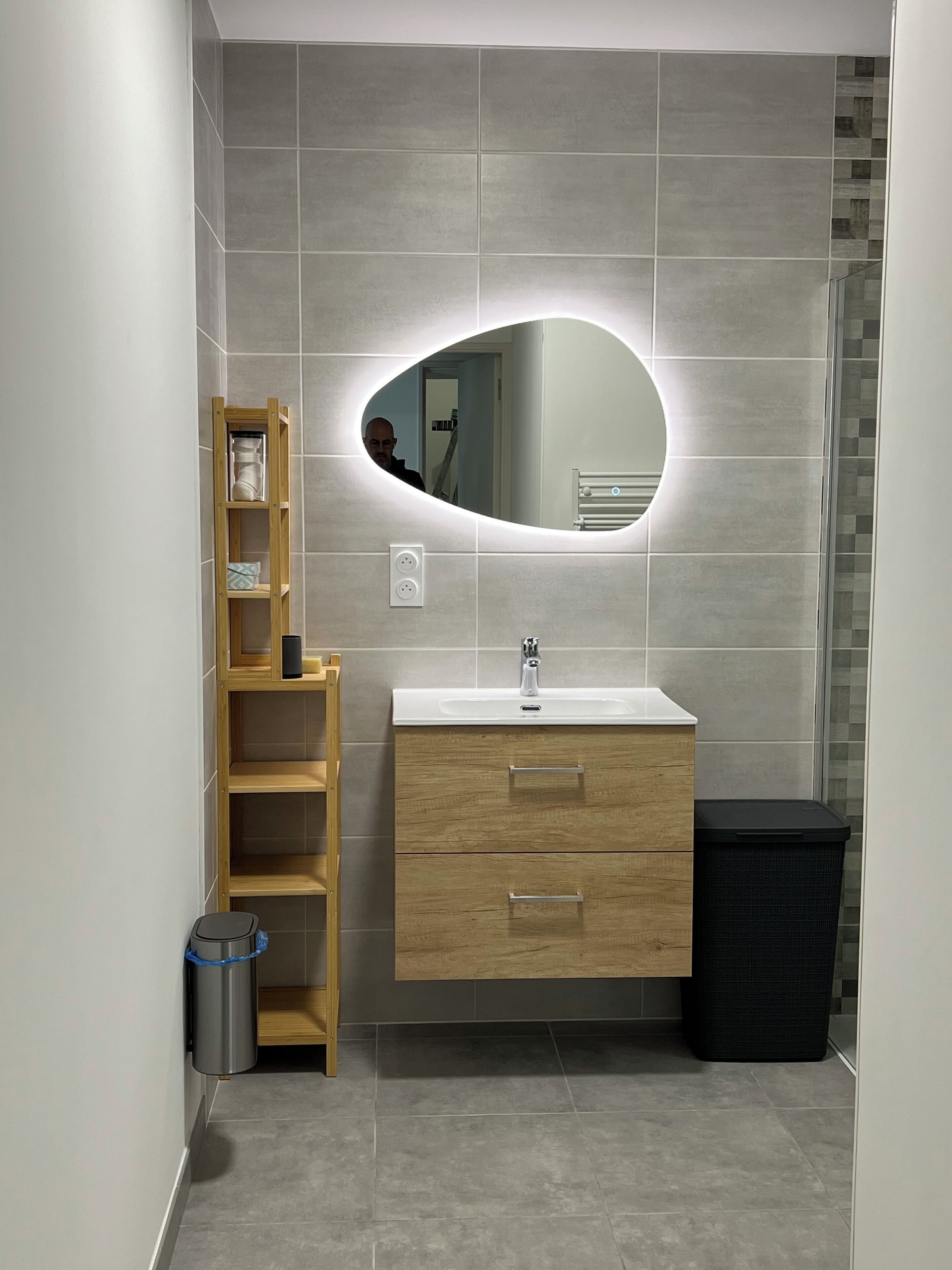 Un baño con tocador de madera, un espejo y un cubo de basura.