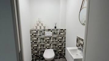 A small, modern bathroom with a toilet, sink, and tiled walls.