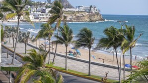 Eine Küstenstadtlandschaft mit Strand, Palmen und einer Statue.