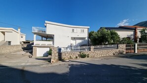 Et moderne hus med to etager, en stenvæg og en hvid balkon.