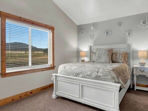 A bedroom with a bed, a nightstand, a lamp, a window with blinds, and decorative wall art. - HOT TUB - WALK TO FOOD, POLAR EXPRESS, DOWNTOWN. CLOSE TO GRAND CANYON!! DOGS OK (Williams)