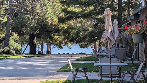 A lakeside patio with outdoor seating and a view of the water. - Cozy Studio Cabin #5 Riverside Point Resort (Park Rapids)