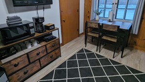 A room with a TV, coffee maker, and a desk with chairs. - Cozy Studio Cabin #5 Riverside Point Resort (Park Rapids)