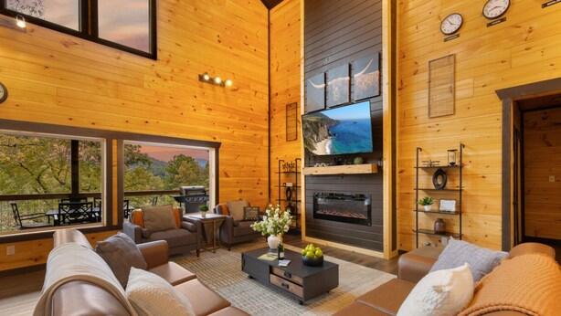 A spacious living room with a fireplace, leather sofas, a coffee table, and a large TV. - Hidden Gem Masterpiece By Ghosal Luxury Lodging  (Gatlinburg)