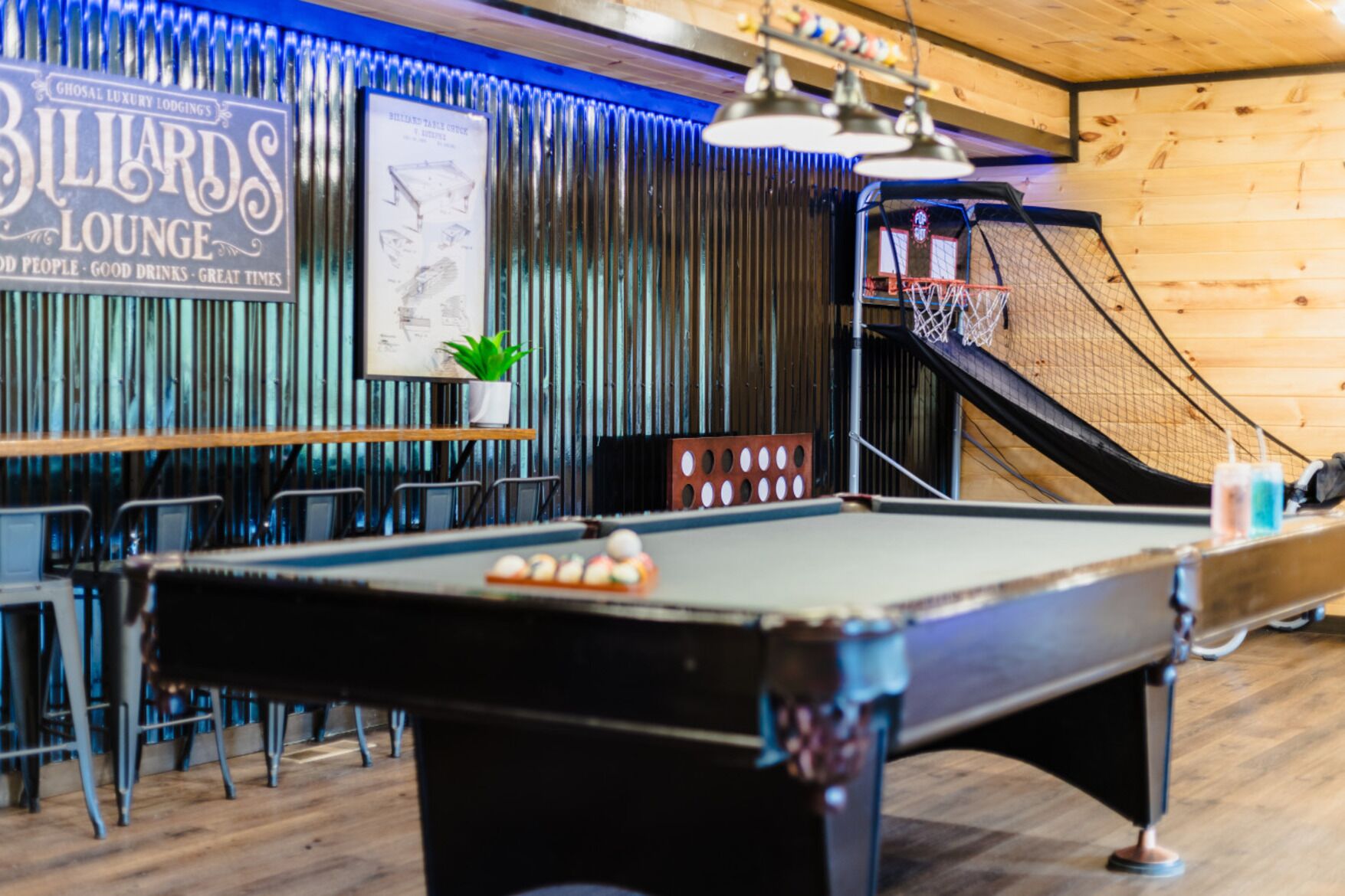 A billiards lounge with a pool table, chairs, and a staircase.