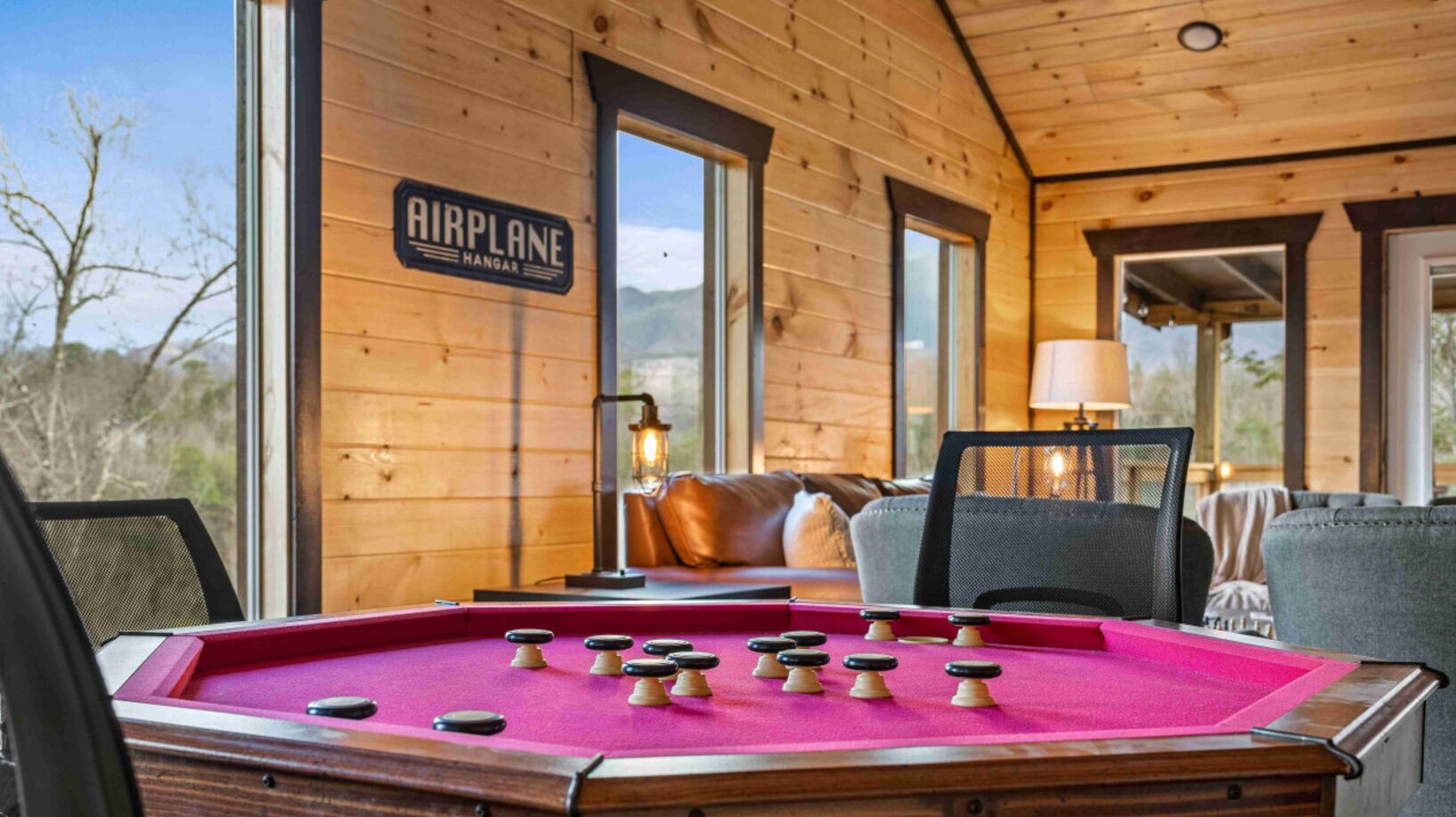 A pool table in a wooden cabin with a sign reading "AIRPLANE HANGAR".