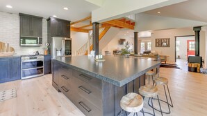 A spacious kitchen with a large island, built-in appliances, and a wooden staircase. - Salt River Access: Mtn-View Star Valley Cabin! (Thayne)