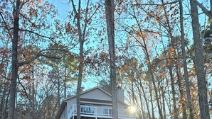 A two-story house with a balcony, surrounded by a forest with autumn leaves. - Charming waterfront retreat on Buggs Island/Kerr Lake—perfect lakeside living! (Clarksville)