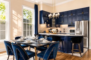 Une cuisine moderne avec des meubles bleu foncé, des appareils en acier inoxydable et un îlot central.