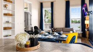 A dining area with a table set for two, a kitchen area with utensils, and a TV mounted on the wall. - 8 Bed 6 Bath Waterfront Views Bourbon Trail w/Firepit HotTub Dome Luxe Amenities (Jeffersonville)