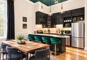 Een moderne keuken met zwarte kastjes, een roestvrijstalen koelkast en een centraal eiland met barstoelen.