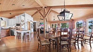 A spacious kitchen with wooden cabinets, a dining area with a large table and chairs, and a ceiling with exposed beams. - On the lake, sleeps 8 with dock and boat lift (Deatsville)