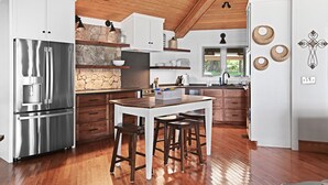 A modern kitchen with wooden flooring, white cabinetry, and stainless steel appliances. - On the lake, sleeps 8 with dock and boat lift (Deatsville)
