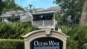 Un panneau indiquant l’accès à « Ocean Walk », avec un parterre de fleurs devant.