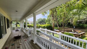 Une véranda en bois avec une balustrade blanche, un banc et un espace aménagé pour un foyer.