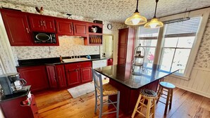 A kitchen with red cabinets, a central island, and wooden flooring. - Your next peaceful getaway in Arlington VT! (Arlington)