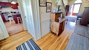 A spacious kitchen with wooden flooring, a dining area with a table and chairs, and a staircase leading to another level. - Your next peaceful getaway in Arlington VT! (Arlington)