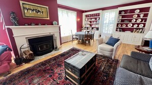 A living room with a fireplace, a coffee table, a sofa, a patterned rug, and a bookshelf. - Your next peaceful getaway in Arlington VT! (Arlington)
